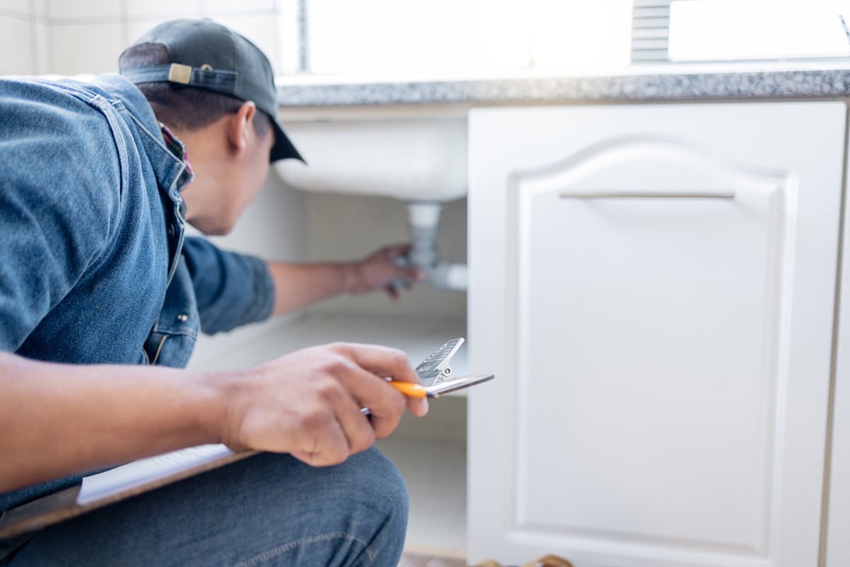 Inspector documenting a plumbing system with a clipboard