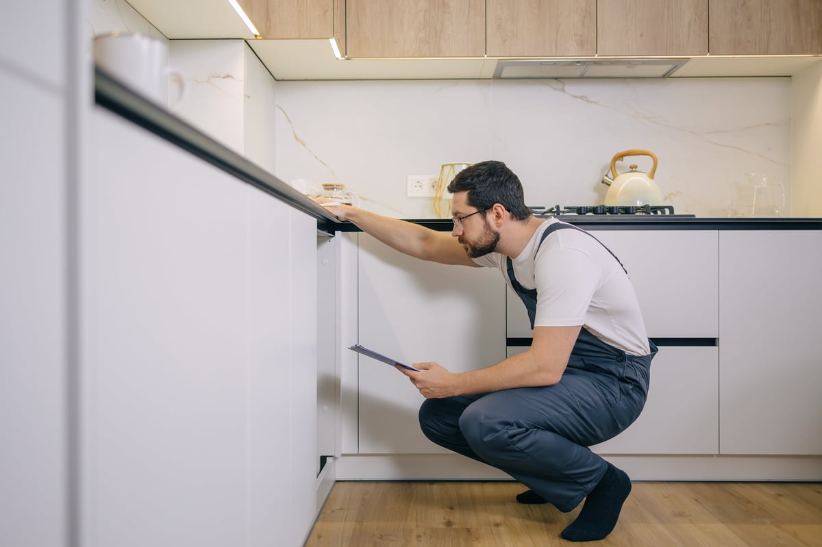 Inspector checking the area under a kitchen sink