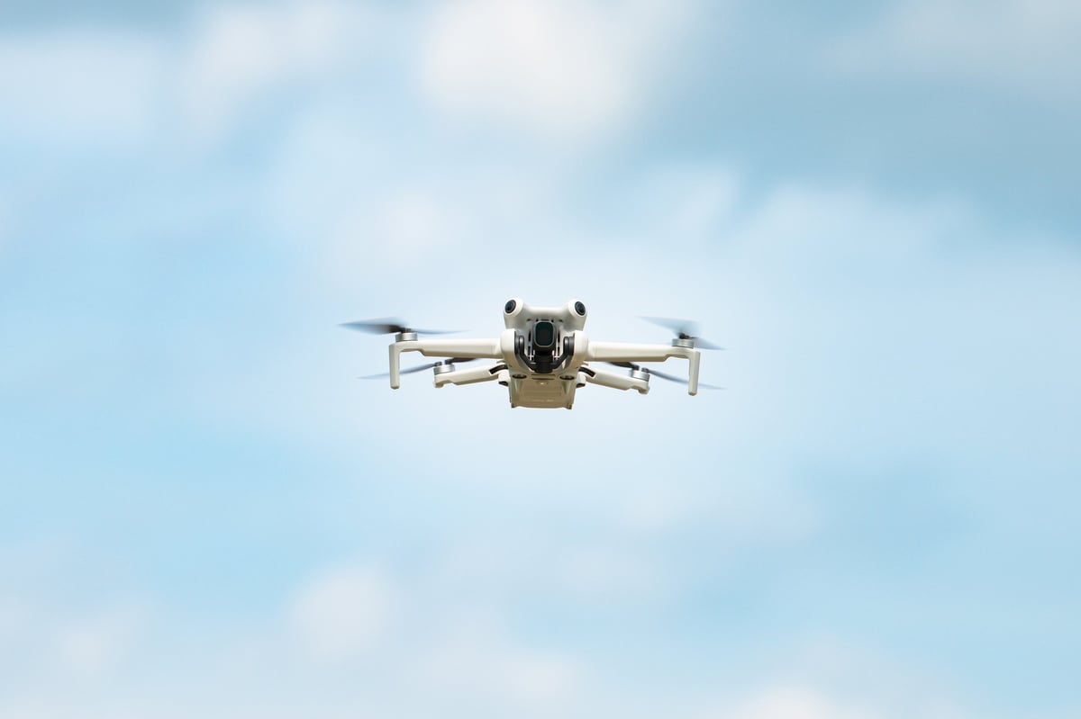 A quadcopter drone in flight with a camera mounted for aerial photography